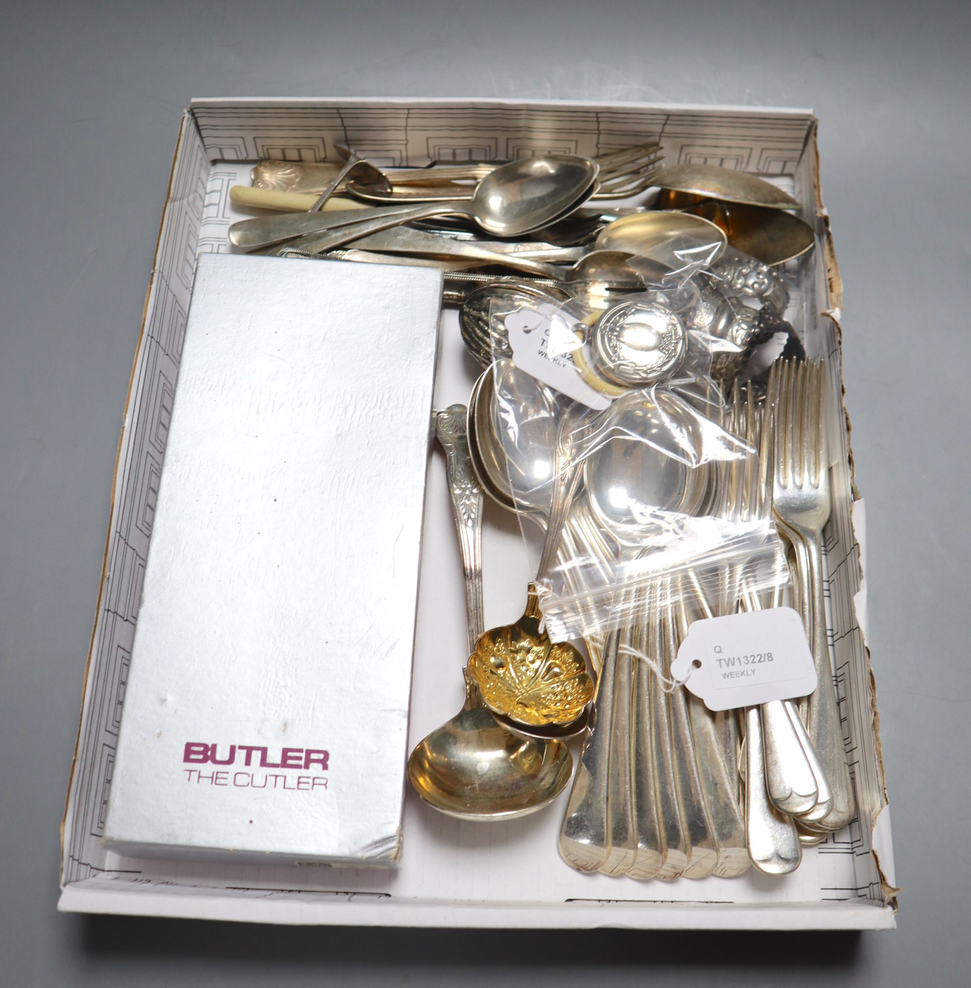 A circular silver babys rattle with ivorine teething ring, three embossed silver napkin rings and a collection of plated flatware,